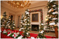 White tree lights twinkle in the shiny red and silver glass ornaments on the snow covered tabletop Christmas trees in the State Dinning Room.