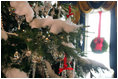 The White House Christmas tree in the Blue Room is adorned with crystals, iridescent glass ornaments fastened to the tree with red satin bows and topped off with soft, cotton snow.