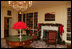 Silver containers filled with red carnations adorn the tables in the Library. The fireplace mantle is decorated with traditional green garland, accented with glass bulbs and red bows.