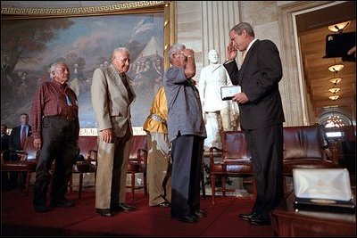 President George W. Bush salutes the Navajo Code Talkers during a ceremony at the U. S. Capitol July 26, 2001. "In war, using their native language, they relayed secret messages that turned the course of battle. At home, they carried for decades the secret of their own heroism," said the President who presented medals to 21 Native Americans who served during World War II.