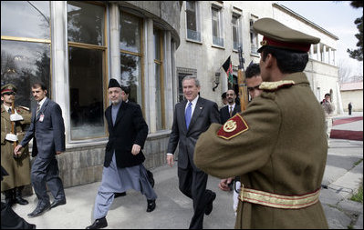 President George W. Bush is accompanied by Afghan President Hamid Karzai at the Presidential Palace in Kabul after President and Mrs. Bush landed in Afghanistan for a brief visit en route to India. During their five-hour stop, they participated in a ceremonial ribbon-cutting at the U.S. Embassy and visited with troops at Bagram Air Base north of the city.