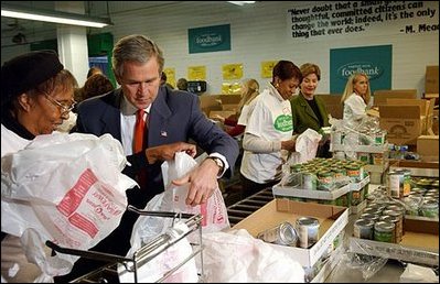 President George W. Bush and Laura Bush help volunteers pack food during their visit to the Capital Area Food Bank in Washington, D.C., Thursday, Dec. 19. "More Americans need to volunteer. There are ways to do so. The USAFreedomCorps.gov on the web page is the place to look," said the President in his remarks. "You can call 1-877-USA-CORPS and find out ways that you can help. If you are interested in being a part of feeding those who hunger, this is a great place to come to." 