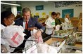 President George W. Bush and Laura Bush help volunteers pack food during their visit to the Capital Area Food Bank in Washington, D.C., Thursday, Dec. 19. "More Americans need to volunteer. There are ways to do so. The USAFreedomCorps.gov on the web page is the place to look," said the President in his remarks. "You can call 1-877-USA-CORPS and find out ways that you can help. If you are interested in being a part of feeding those who hunger, this is a great place to come to." 