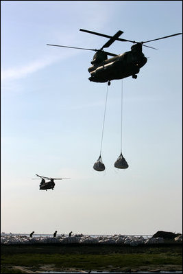 Helicopters lift sandbags that will be dropped into the area of the levee break to facilitate repairs to 17th street levee in New Orleans, Louisiana Thursday, September 8, 2005.