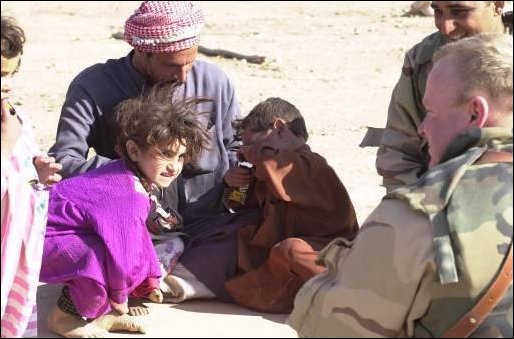 US soldiers give the children, of a relocated family, candy to brighten their day.