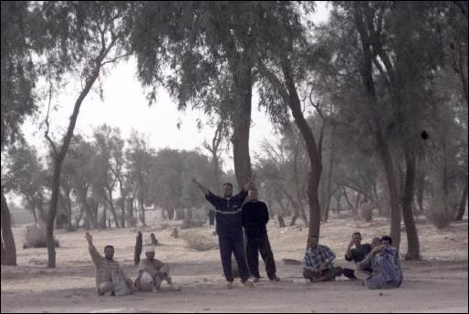 A group of Iraqi people wave at the passing coalition forces