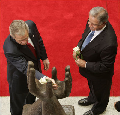 With President Oscar Berger looking on, President George W. Bush lays a white rose in the palm of the Peace Monument, symbolizing 24 hours of peace, during arrival ceremonies Monday, March 12, 2007, at the National Palace of Culture in Guatemala City. White House photo by Paul Morse