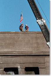 Echoing the actions of the soldiers who raised the flag in victory at Iwo Jima during World War II, firefighters post the American Flag directly into the scarred stone of the Pentagon Sept. 12. White House photo by Paul Morse.