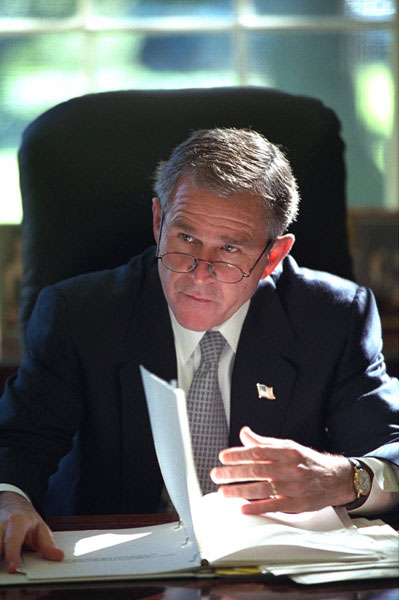 Working at his desk in the Oval Office, President George W. Bush prepares for his first meeting with the Homeland Security Team Oct. 29, 2001. White House photo by Eric Draper.