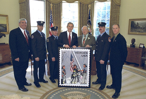 President George W. Bush stands for photos at the unveiling of the Postal Service's new stamp Commemorating the efforts of recovery workers in the aftermath from the attack upon the World Trade Center, President George W. Bush unveils a new stamp in the Oval Office March 11, 2002. Standing with the President from left to right are Postmaster General Jack Potter, Firefighter Bill Eisengrein, Firefighter George Johnson, Congressman Gary Ackerman, Firefighter Dan Williams and Photographer Thomas E. Franklin. White House photo by Tina Hager.