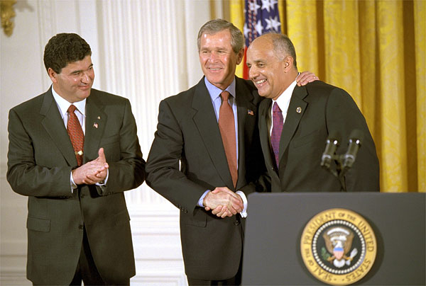 President George W. Bush embraces his nominee for Surgeon General, Dr. Richard Carmona, as Dr. Elias Zerhouni, left, applauds in the East Room Tuesday, March 26. Dr. Zerhouni is nominated to be the Director of the National Institute of Health. White House photo by Tina Hager.