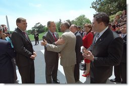 Accompanied by Secretary of Housing and Urban Development Mel Martinez (immediate left of the President), President George W. Bush meets with members of his staff on the South Lawn after posing for a group portrait with approximately 160 White House hispanic employees. White House photo by Eric Draper.