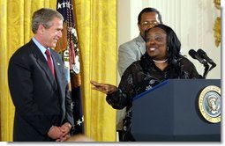 President George W. Bush receives praise from Welfare to Work graduate Ann Briscoe and her husband Alfred at an East Room event at the White House on June 4, 2002. White House photo by Paul Morse.