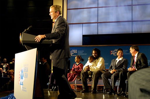 President George W. Bush addresses the White House Conference on Increasing Minority Homeownership at The George Washington University Tuesday, Oct. 15. Sitting behind the President are new homeowners the Horton Family and Kim Berry, who is laughing with Secretary of Housing and Urban Develop Mel Martinez. White House photo by Paul Morse