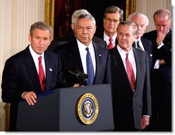 Accompanied by a bipartisan group of legislators, President George W. Bush signs H.J. Resolution 114 authorizing the use of force against Iraq in the East Room Wednesday, Oct. 16. "The resolution I'm about to sign symbolizes the united purpose of our nation, expresses the considered judgment of the Congress, and marks an important event in the life of America," said President Bush. Standing next to the President are Secretary of State Colin Powell, center, and Secretary of Defense Donald Rumsfeld, right. White House photo by Paul Morse.