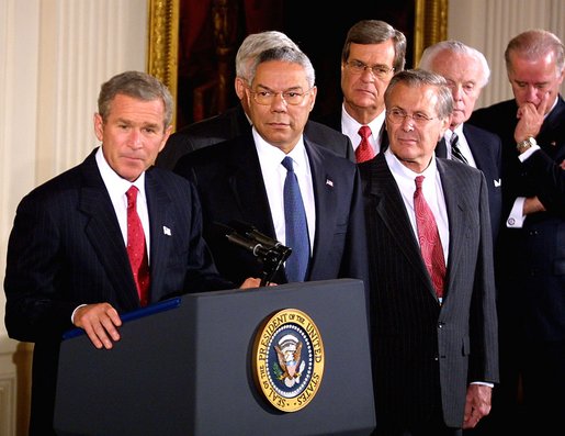 Accompanied by a bipartisan group of legislators, President George W. Bush signs H.J. Resolution 114 authorizing the use of force against Iraq in the East Room Wednesday, Oct. 16. "The resolution I'm about to sign symbolizes the united purpose of our nation, expresses the considered judgment of the Congress, and marks an important event in the life of America," said President Bush. Standing next to the President are Secretary of State Colin Powell, center, and Secretary of Defense Donald Rumsfeld, right. White House photo by Paul Morse.