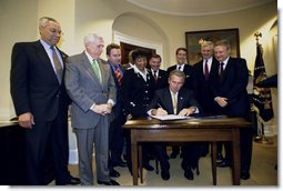 President George W. Bush signs the Sudan Peace Act in the Roosevelt Room at the White House, Oct. 21, 2002. Standing with the President are lawmakers and the Secretary of State Colin Powell, far left, and former Senator and special envoy for peace to the Sudan John Danforth, second from right. White House photo by Eric Draper.