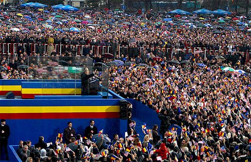 Standing with Romanian President Iliescu, President George W. Bush waves to thousands of Romanians in Revolution Square in Bucharest, Romania, Nov. 23. The square is the site of the 1989 revolt that toppled communist rule and where the Romanian people denounced the dictator Nicolae Ceausescu. "And here, in December of 1989, you broke the silence of your captivity," remarked President Bush. "From that balcony, the dictator heard your voices and faltered -- and fled. Two generations of bitter tyranny ended, and all the world witnessed the courage of Romania, the courage that set you free." White House photo by Paul Morse