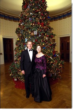 President George W. Bush and Laura Bush stand before the Blue Room Christmas Tree Sunday, December 8, 2002 prior to hosting a reception for the Kennedy Center Honorees. Mrs. Bush is wearing a floor length gown designed by Arnold Scaasi.  White House photo by Eric Draper