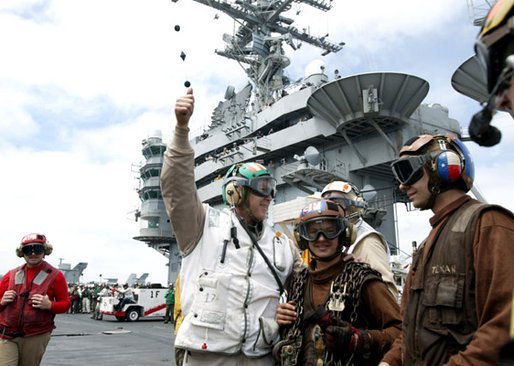 After a successful landing, President George W. Bush gives the thumbs-up sign as he meets with flight crews on the deck of the USS Abraham Lincoln Thursday, May 1, 2003. White House photo by Paul Morse