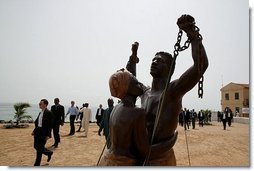 President George W. Bush walks with President Abdoulaye Wade on Goree Island Tuesday, July 8, 2003. The statue in the foreground is in memory of Africans who left the continent as slaves.  White House photo by Paul Morse