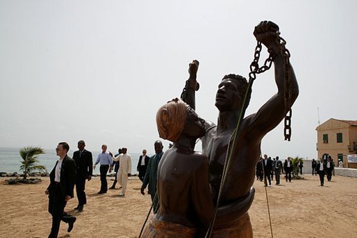 President George W. Bush walks with President Abdoulaye Wade on Goree Island Tuesday, July 8, 2003. The statue in the foreground is in memory of Africans who left the continent as slaves. White House photo by Paul Morse.