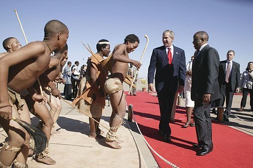 Walking with President Festus Gontebanye Mogae of Botswana, President George W. Bush and Laura Bush (not pictured) are greeted by traditional dancers upon their arrival at Sir Seretse Khama International Airport Thursday, July 10, 2003.