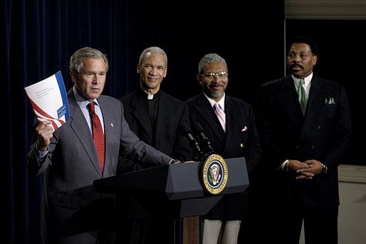 Holding up a book about his Faith-Based Initiatives, President George W. Bush talks with urban leaders in the Eisenhower Executive Office Building Wednesday, July 16, 2003. Standing behind the President are, from left, Rev. Bishop John Huston Ricard of Fla., Rev. Eugene F. Rivers III of Mass., and Tony Evans of Texas. White House photo by Eric Draper.