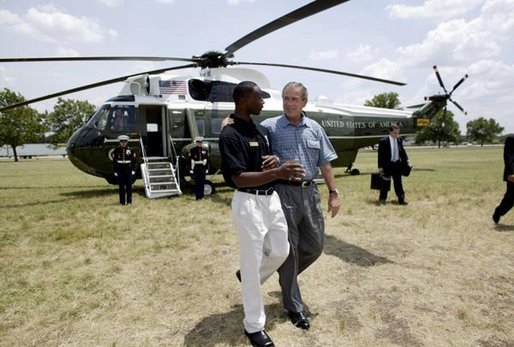 President George W. Bush walks with YMCA volunteer Andrew Simpson after arriving on Marine One in Dallas, Texas, Friday, July 18, 2003. White House photo by Paul Morse