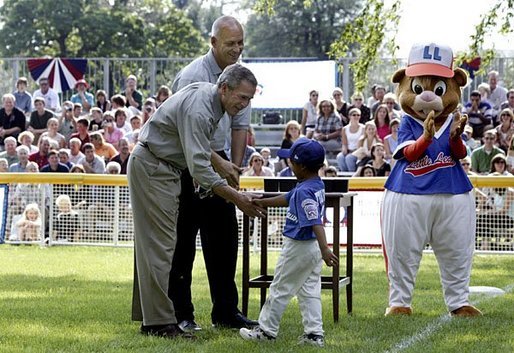 President George W. Bush and Honorary Commissioner Cal Ripken present a little leaguer with a warm congratulations and an autographed baseball after playing the last game of the 2003 White House South Lawn Tee Ball season Sunday, Sept. 7, 2003. White House photo by Lynden Steele.