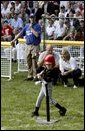 A little slugger from Kalamazoo, Mich., takes his hit under the expert gaze of Honorary Commissioner and Baltimore Orioles great Cal Ripken and Olympic Gold Medalist and Honorary Third Base Coach Dot Richardson during the last game of the White House South Lawn Tee Ball season Sunday, Sept. 7, 2003. White House photo by Lynden Steele.