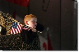 Keeping a grip on his souvenir flags, a boy listens to President George W. Bush at Pease Air National Guard Base in Portsmouth, N.H., Thursday, Oct. 9, 2003. White House photo by Tina Hager.