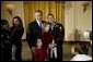 President George W. Bush poses for pictures with a soldier and children during a reception held for children of deployed military personnel at the White House Monday, Dec. 8, 2003. A variety of activities were held for the children, including a performance of selected scenes from The Nutcracker and a visit by Santa Claus. White House photo by Eric Draper