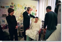 President George W. Bush speaks to a relative of U.S. Army Sergeant First Class Joseph Briscoe, of Liberty, Texas, after presenting Sgt. Briscoe The Purple Heart for injuries he sustained while serving in Iraq. President Bush visited troops at Walter Reed Army Medical Center in Washinton, D.C., Thursday, December 18, 2003. Laura Bush and Sgt. Briscoe’s brother, Ira, look on.  White House photo by Eric Draper