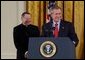 President George W. Bush addresses The National Catholic Educational Association in the East Room Friday, Jan. 9, 2004. The Association represents more than 200,000 educators serving 7.6 million students in Catholic education at all levels. Pictured with the President is His Excellency Gregory Aymond, Bishop of Austin, Texas. White House photo by Tina Hager