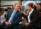 President George W. Bush and accounting clerk Neomi Gonzalez react on stage during a conversation on the economy with employees at Nu-Air Manufacturing Company in Tampa, Florida, Monday, Feb. 16, 2004. White House photo by Eric Draper