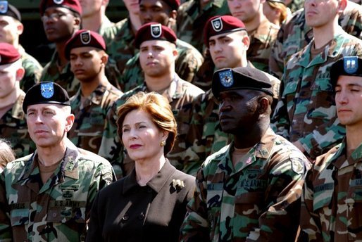 Laura Bush listens while President George W. Bush delivers his remarks at Fort Campbell, Ky., Thursday, March 18, 2004. "Since we last met, you helped to build medical clinics and to rebuild schools. By your decency and compassion, you are helping the Iraqi people to reclaim their country. Because you care, you're helping the Iraqis live as free people," said the President. White House photo by Tina Hager