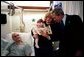 President George W. Bush reads a baby book with U.S. Army Reservist First Lieutenant Brandan Mueller of Webster Groves, Mo., his wife Amanda, and their daughter Abigail at Walter Reed Army Medical Center in Washington, D.C., Friday, March 19, 2004. Lt. Mueller was injured while serving in Operation Iraqi Freedom. White House photo by Eric Draper.