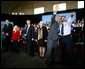 President George W. Bush waves to the audience with student Tony Johnson after a conversation on job training and the economy at South Arkansas Community College in El Dorado, Ark., Tuesday, April 6, 2004. White House photo by Eric Draper