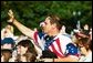 People lined along Constitution Avenue wave to Nancy Reagan as she passes by during the funeral procession of former President Ronald Reagan, Wednesday, June 9, 2004. White House photo by Joyce Naltchayan.