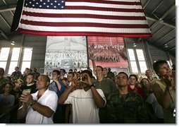 MacDill Air Force Base mIlitary personnel listen to President George W. Bush deliver remarks as two screens display a live feed of military personnel in Afghanistan, left, and Iraq, Wednesday, June 16, 2004.   White House photo by Eric Draper