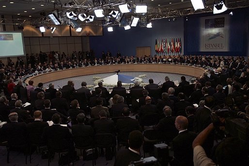 Hosted by Turkey, the 17th NATO Summit is the first meeting of its now 26 member nations after the accession of seven new countries in March. President George W. Bush and Secretary of State Colin Powell are pictured just left of the flags during the opening session of the summit in Istanbul, Monday, June 28, 2004. White House photo by Paul Morse.