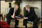 President George W. Bush receives the results of the 2004 Monitoring the Future study from Director John Walters of the Office of National Drug Control Policy in the Oval Office Tuesday, Dec. 21, 2004. The study measures drug, alcohol and cigarette use among adolescent students nationwide. This year's report found that drug use among teens has declined 17 percent since 2001. White House photo by Paul Morse