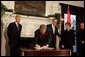 President George W. Bush signs a condolence book for the victims of the recent tsunami during a visit to the Embassy of India in Washington, D.C., Monday, Jan. 3, 2005. Also signing to express their condolences are Laura Bush and former Presidents Bush and Clinton. White House photo by Susan Sterner.