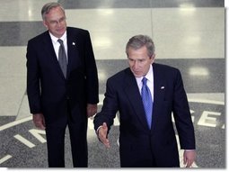 Central Intelligence Agency Director Porter Goss listens as President Bush delivers a brief statement to the media after visiting with CIA employees at their headquarters Thursday, March 3, 2005, in Langley, Va.  White House photo by Paul Morse