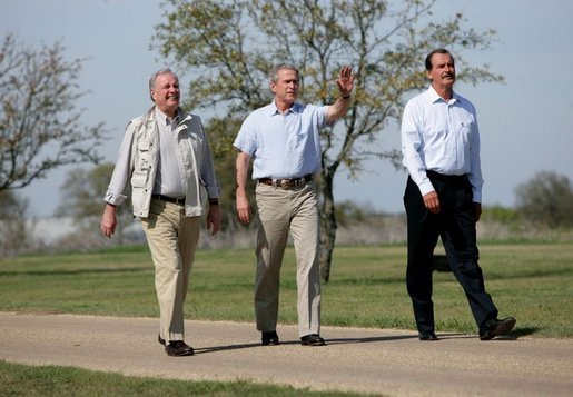 Hosting a lunch and tour at his ranch, President George W. Bush waves to the press while walking with Canadian Prime Minister Paul Martin, left, and Mexican President Vicente Fox in Crawford, Texas, March 23, 2005. White House photo by Eric Draper White House photo by Eric Draper