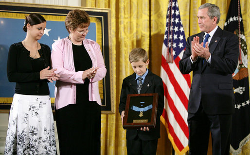 David Smith, 11-year-old son of Sgt. 1st Class Paul Smith, holds his father's Medal of Honor, awarded Monday, April 4, 2005, posthumously by President Bush during ceremonies at the White House. Looking on are Smith's wife, Birgit, and step-daughter Jessica.White House photo by Paul Morse