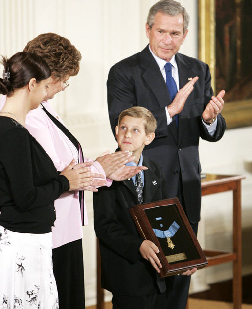 Young David Smith holds his father's Medal of Honor -- presented by President Bush -- as he looks to his mother, Birgit Smith, during ceremonies Monday, April 4, 2005, at the White House. Sgt. 1st Class Paul Smith, was mortally wounded while saving other members of his task force during Operation Iraqi Freedom.White House photo by Paul Morse