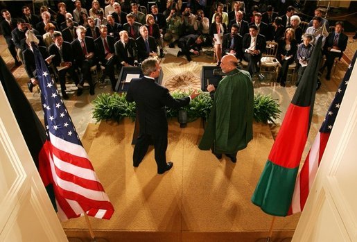 With the media looking on, President George W. Bush reaches out to shake hands with President Hamid Karzai of Afghanistan after a joint press availability Monday, May 23, 2005, in the East Room of the White House. White House photo by Paul Morse