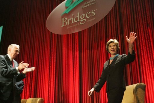 Laura Bush acknowledges the applause of the crowd as she is introduced at the Marriott Foundation for Disabilities Gala Dinner, June 14, 2005 at the Marriott Wardman Park Hotel in Washington, D.C. J.W. (Bill) Marriott, Jr., left, is seen welcoming Mrs. Bush to the podium. White House photo by Krisanne Johnson